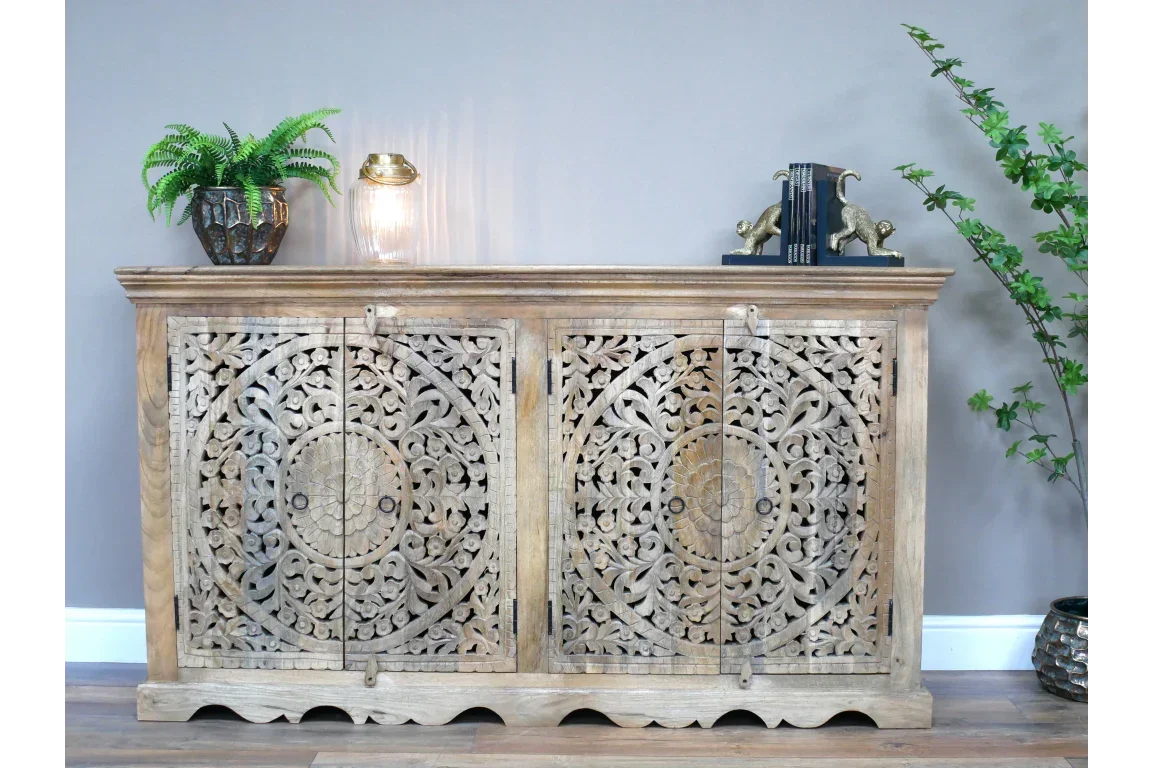 Natural wood sideboard with hand-carved floral doors, styled with plants and decor accents