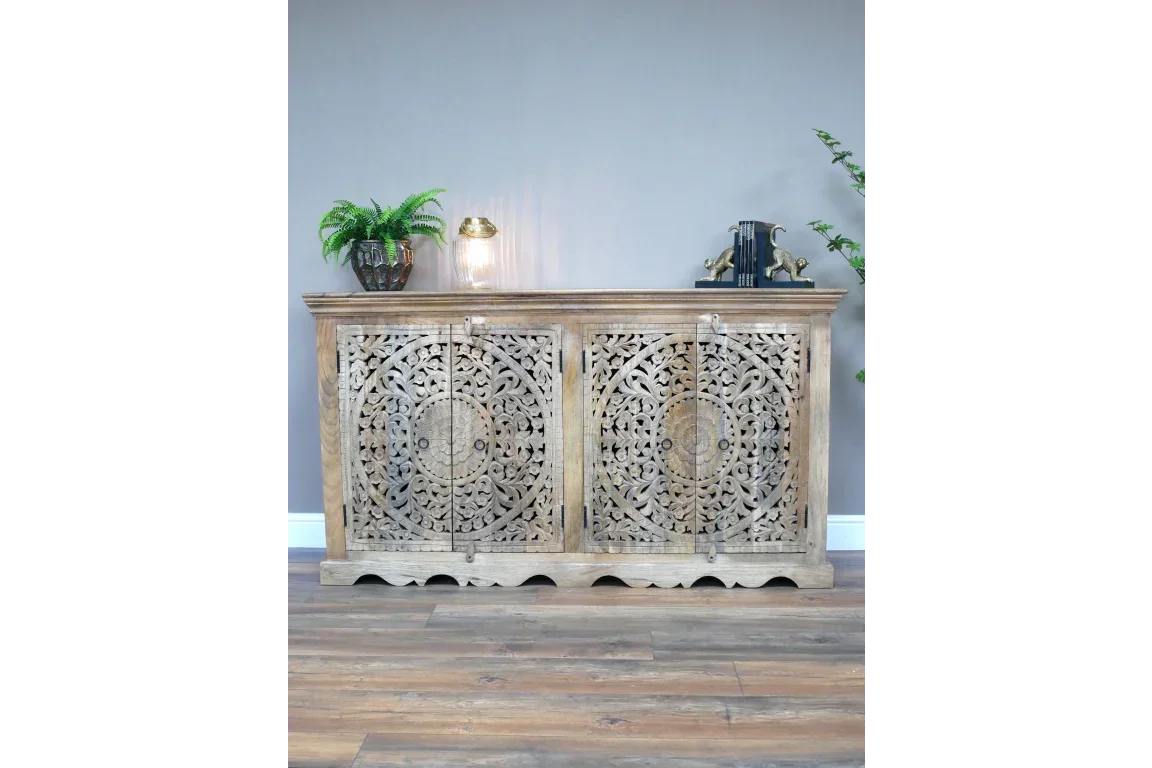 Carved wood sideboard with ornate floral patterns and natural finish against a grey wall
