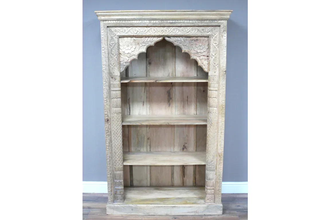 Hand carved wooden bookcase with ornate arch detail and four open shelves against grey wall