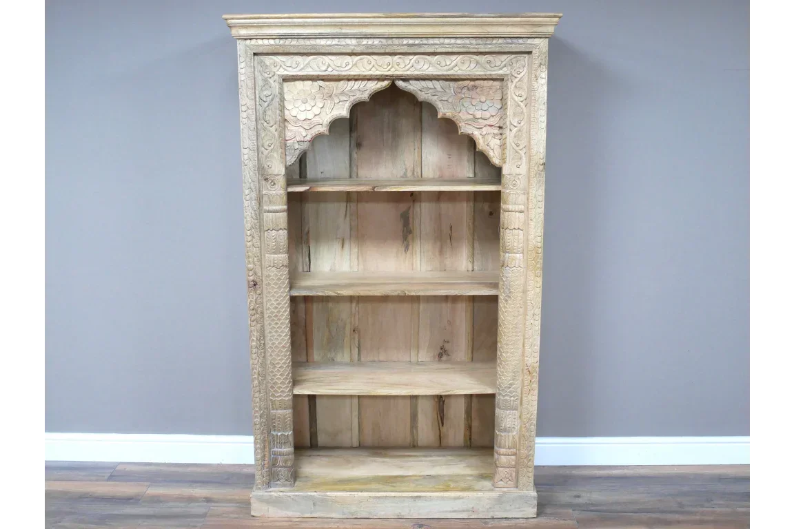 Carved wooden bookshelf with ornate detailing and open shelves against grey wall