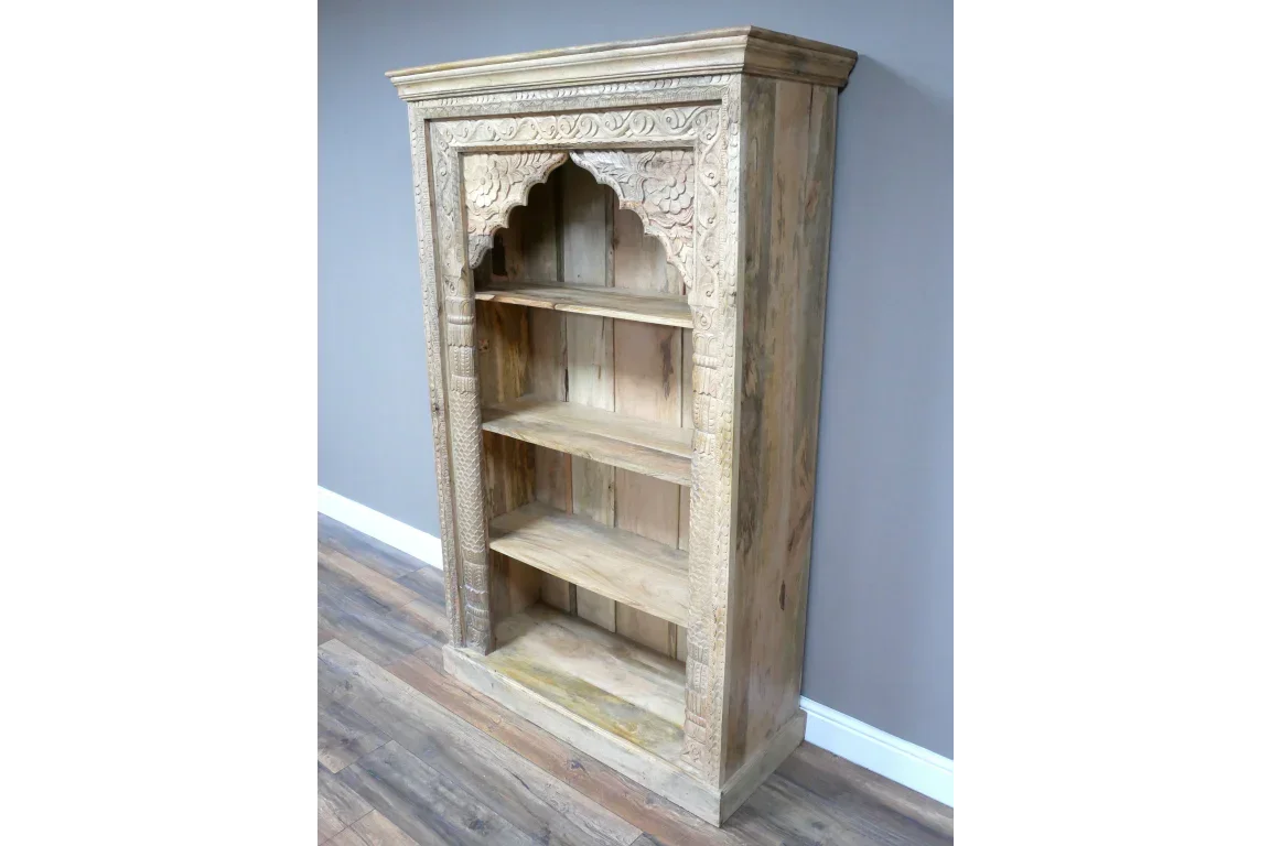 Carved wood bookcase with arched detailing and three open shelves against a grey wall
