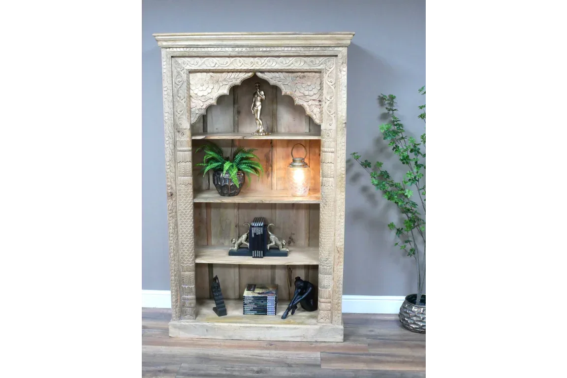 Carved wooden bookcase with decorative arch, shelves styled with books and ornaments