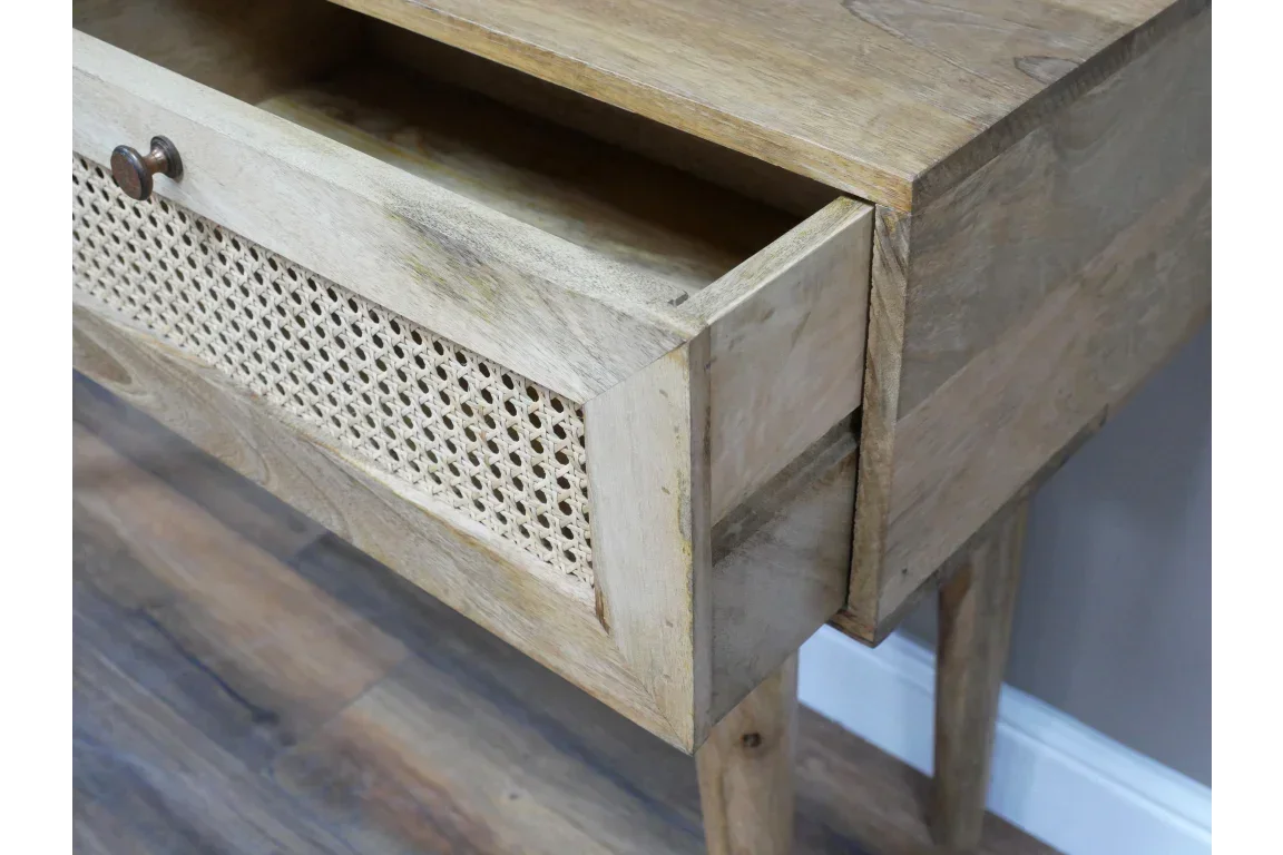 Natural wood console table with open drawer and rattan front detail on wooden floor