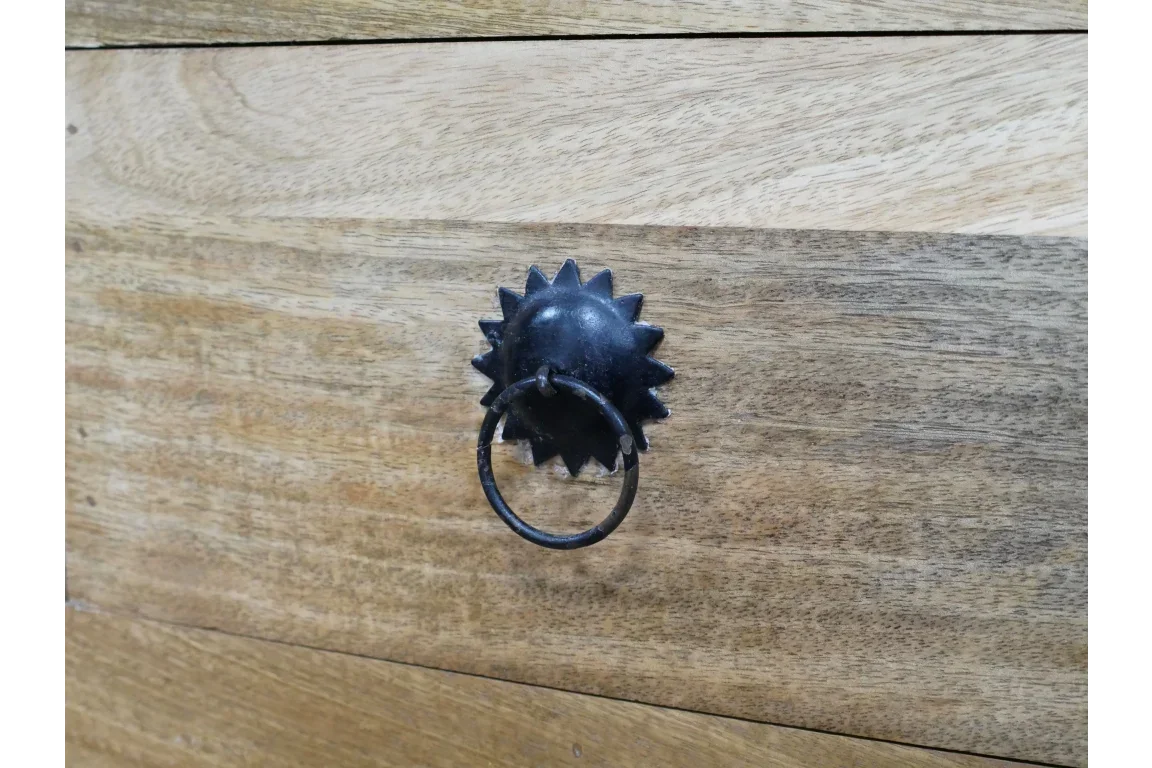Black metal ring handle on natural wood drawer front, close-up furniture detail
