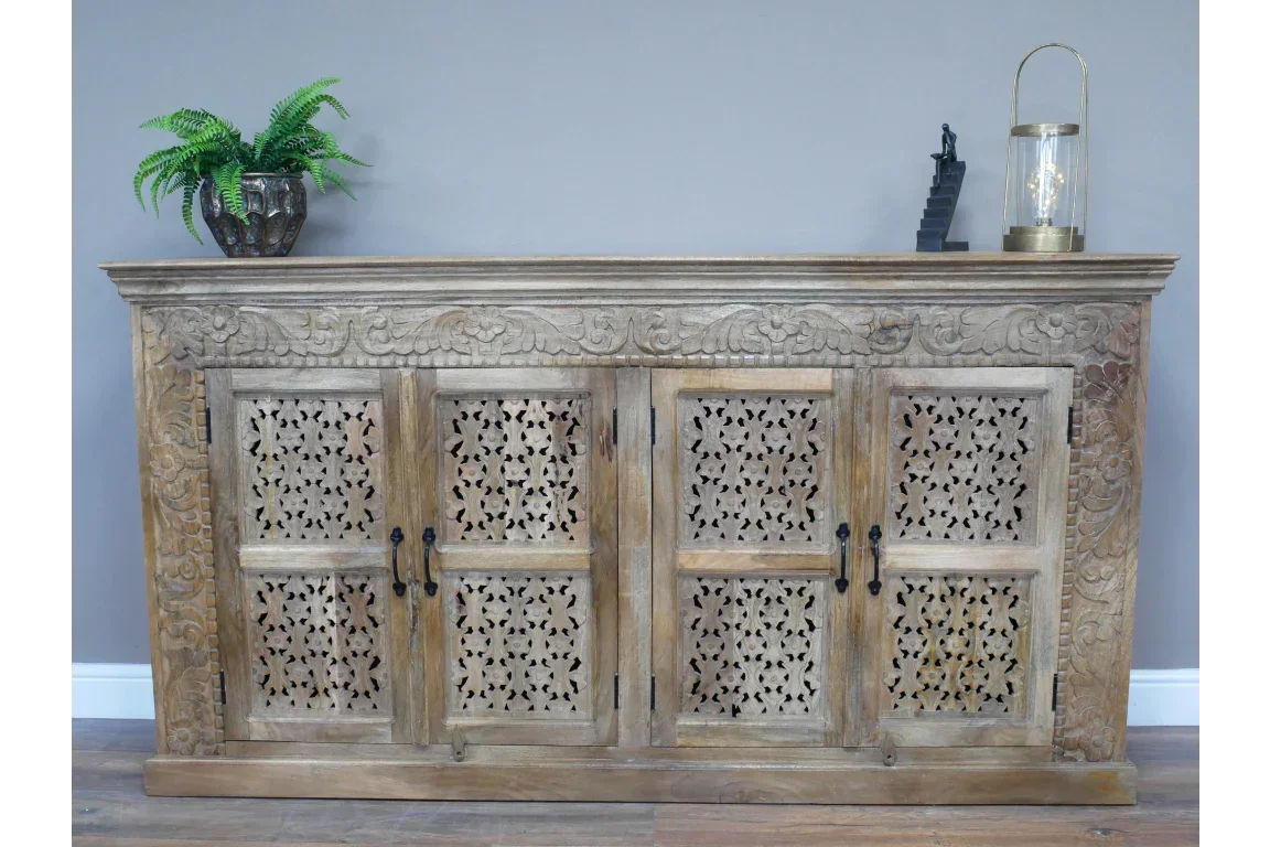 Carved wooden sideboard with floral cut-out doors and decorative top, styled with home decor
