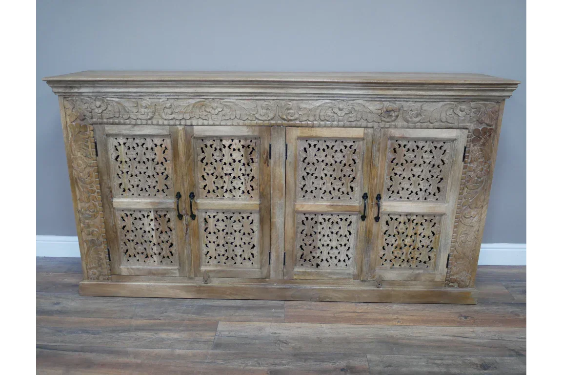 Natural wood sideboard with carved floral panels and four cabinet doors on wooden floor
