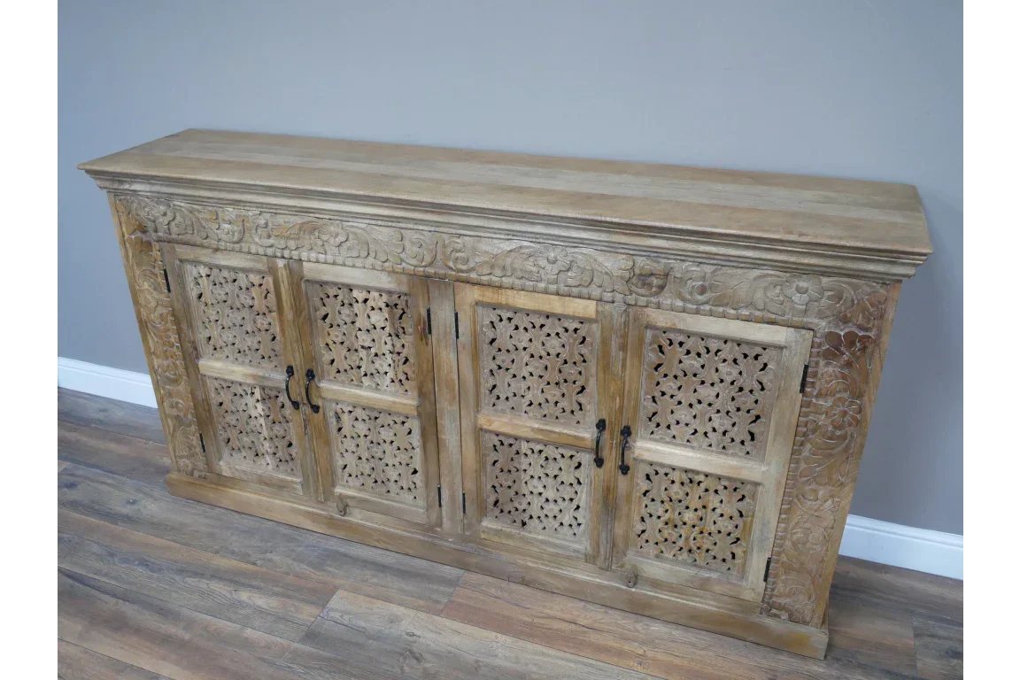 Carved wooden sideboard with floral panel doors and natural finish on wood floor