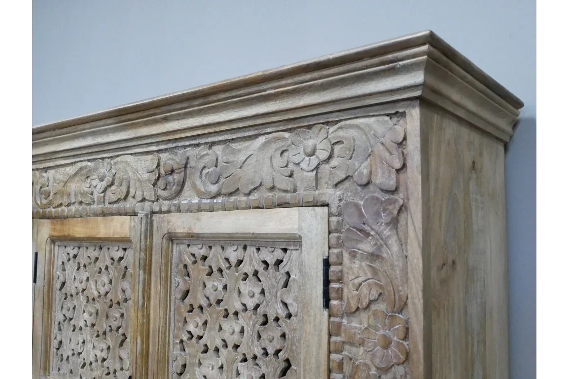 Carved wooden cabinet with floral details and intricate panel design, corner close-up view