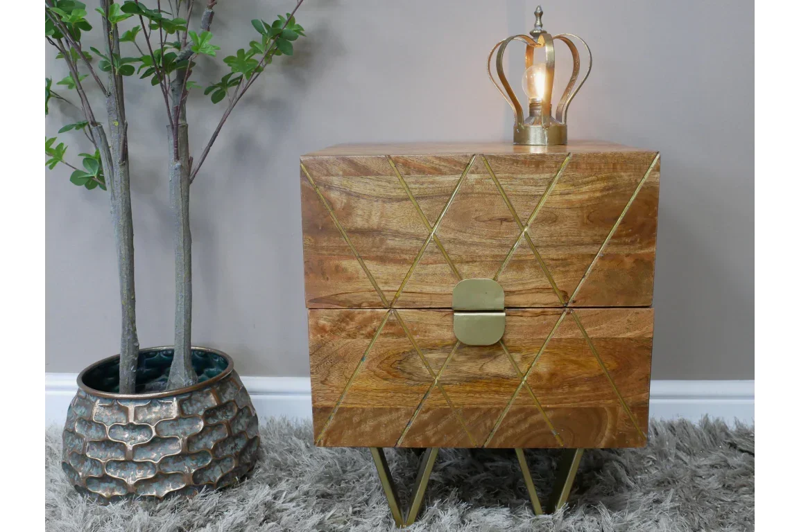 Wooden bedside table with gold geometric accents and metal legs, styled with decorative lamp