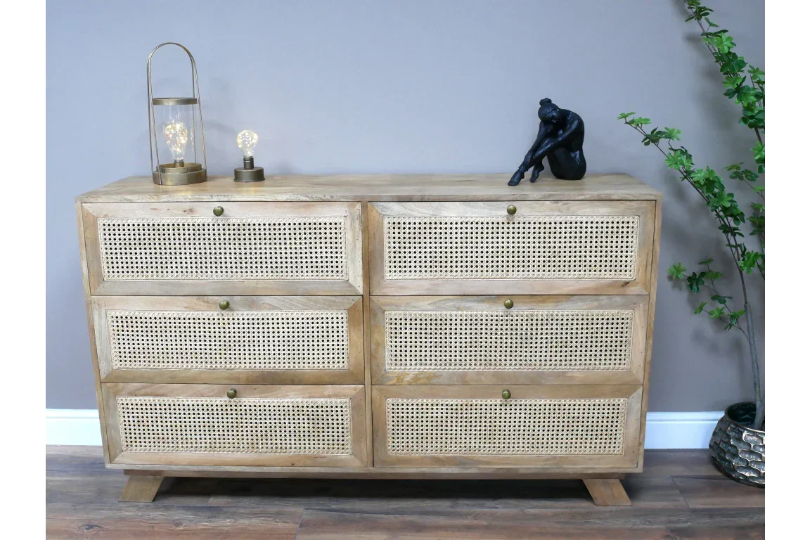 Wooden rattan sideboard with six drawers, decorative lamps, sculpture, and plant beside