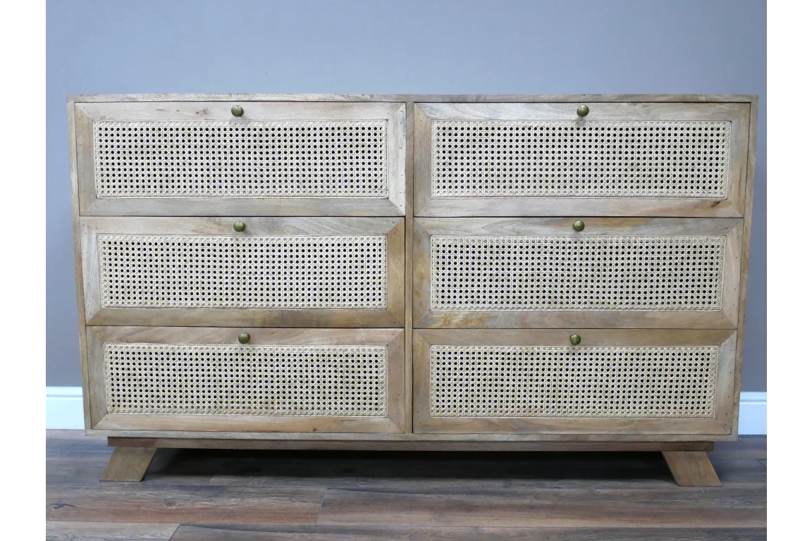 Six drawer wooden sideboard with rattan drawer fronts and brass knobs on wooden floor