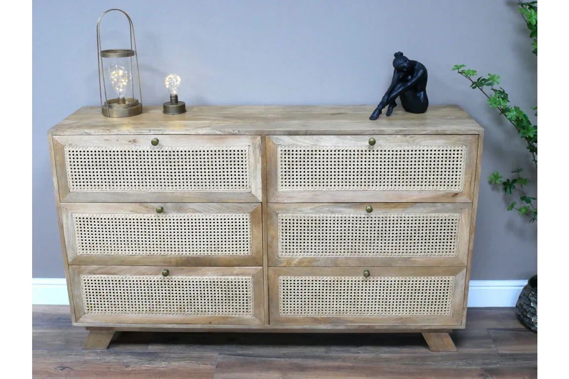 Natural wood chest of drawers with rattan panels and decorative items on top