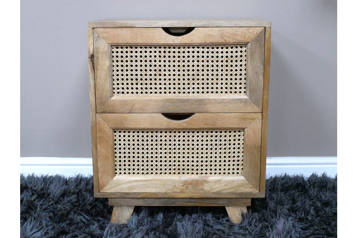 Natural wood bedside table with two rattan drawers on grey rug against light wall