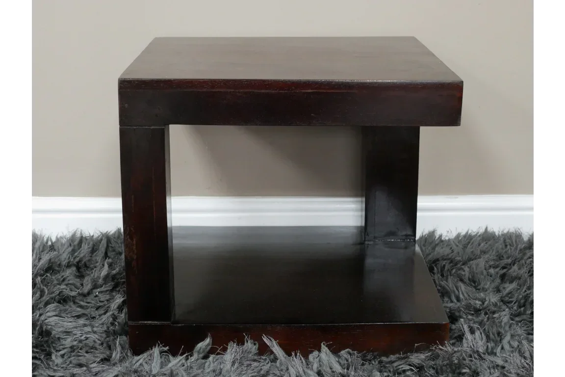 Dark wood side table with open shelf, modern design, placed on grey shaggy rug