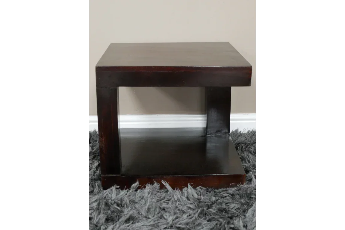 Dark wood side table with modern open shelf design on grey rug