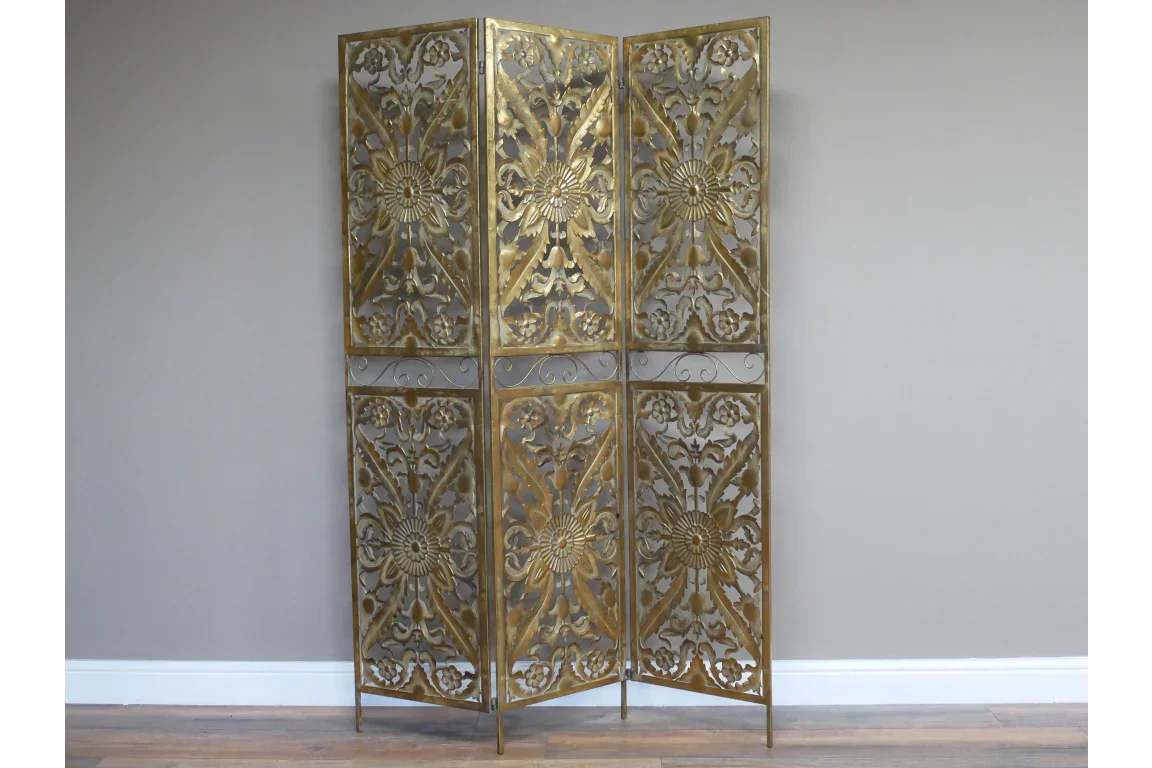 Gold metal room divider with floral and geometric cut-out panels, shown against a neutral wall