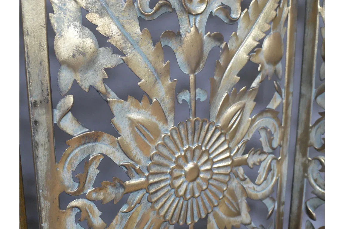 Closeup of gold metal wall art with floral and leaf pattern detail