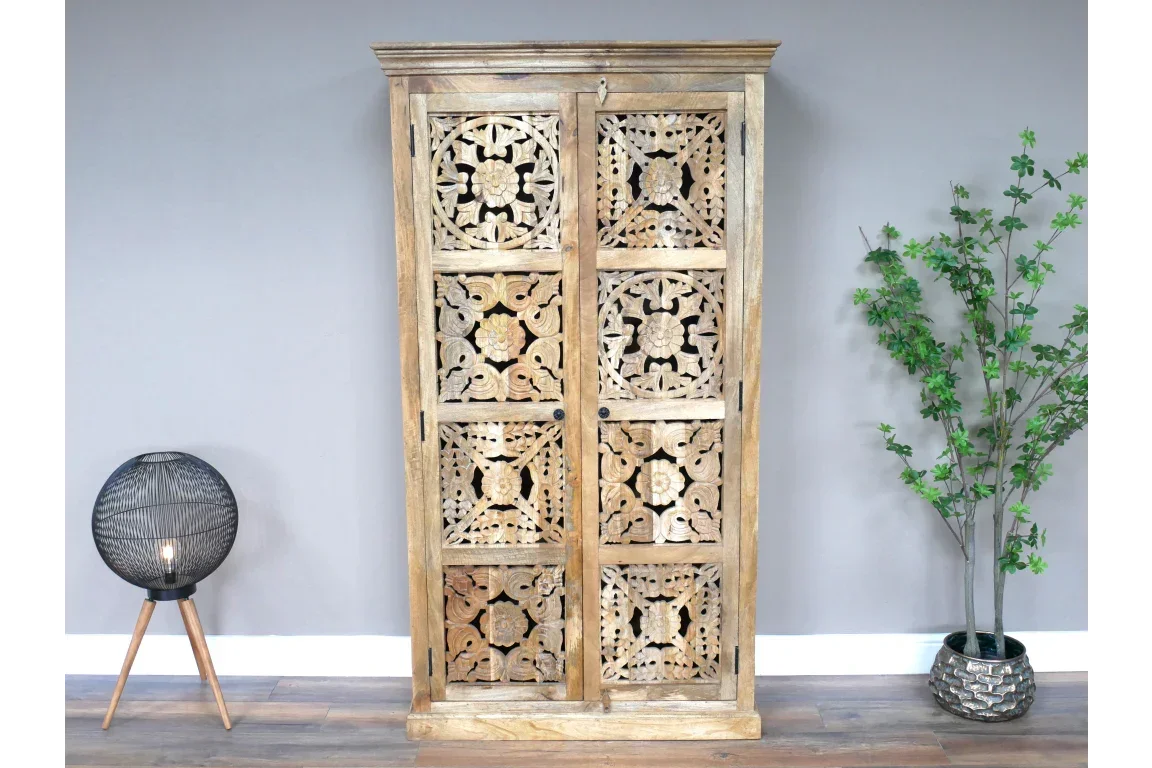 Wooden carved wardrobe with intricate floral panels, placed against a light grey wall