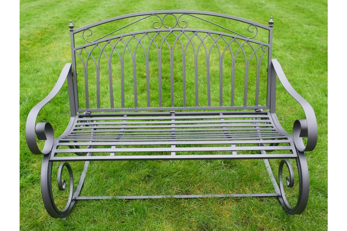 black metal garden bench with scroll arms and slatted seat on green grass
