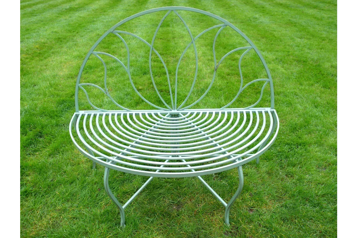 Metal garden bench with curved backrest and leaf design on grass lawn