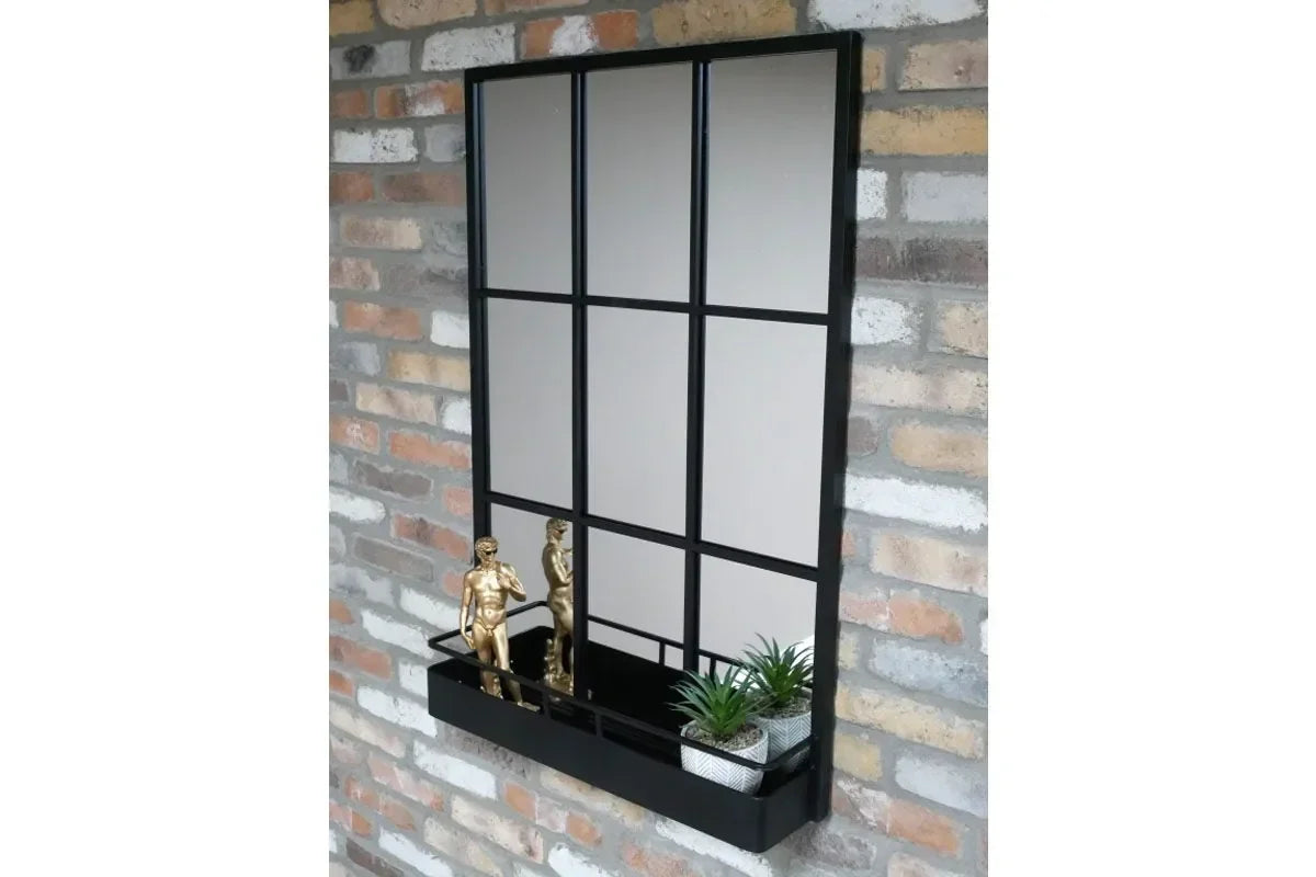 Black grid wall mirror with shelf, gold statues, and small plants on brick wall