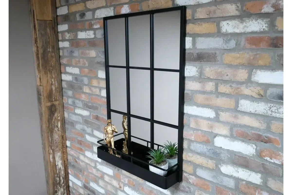 Rectangular black metal wall mirror with shelf, small gold statues, and potted plants