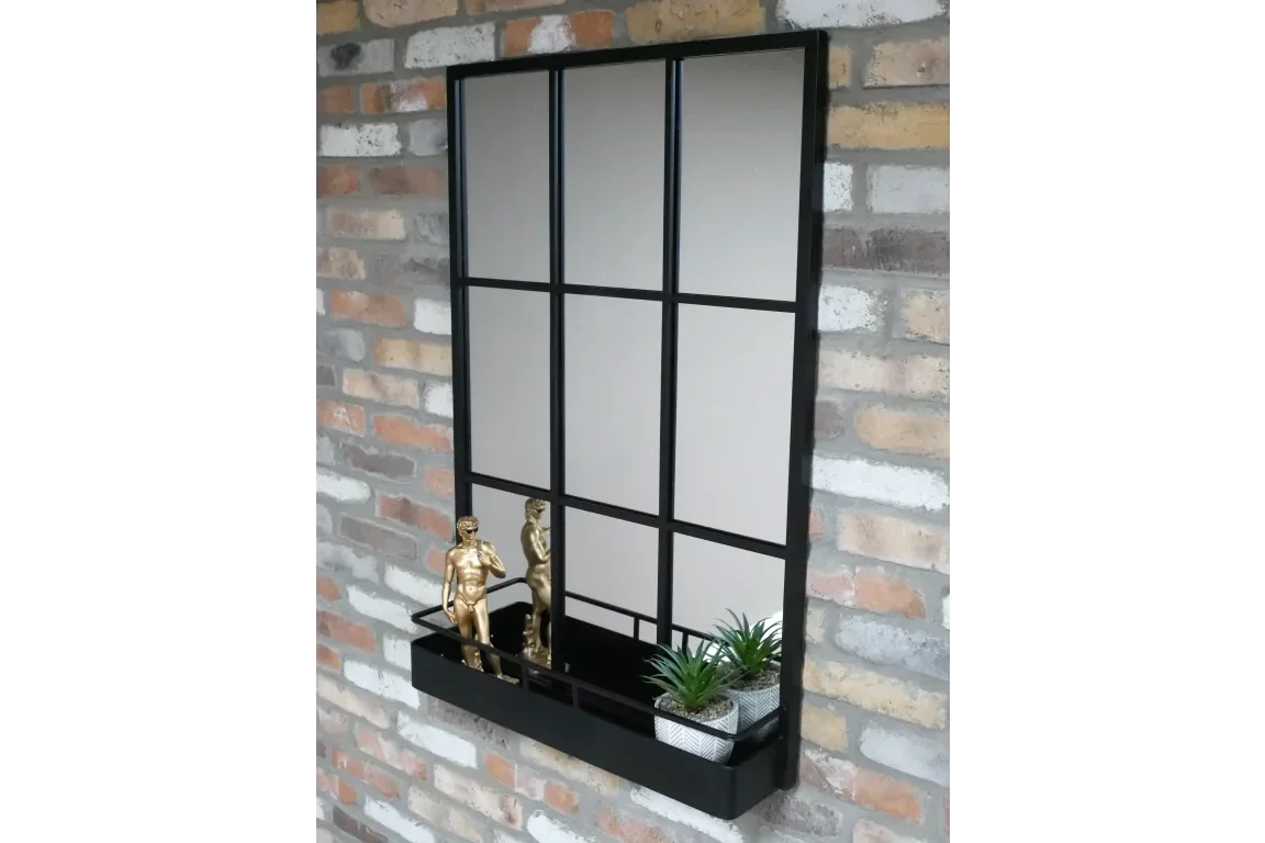Black industrial wall mirror with shelf, gold figurines, and small potted plants