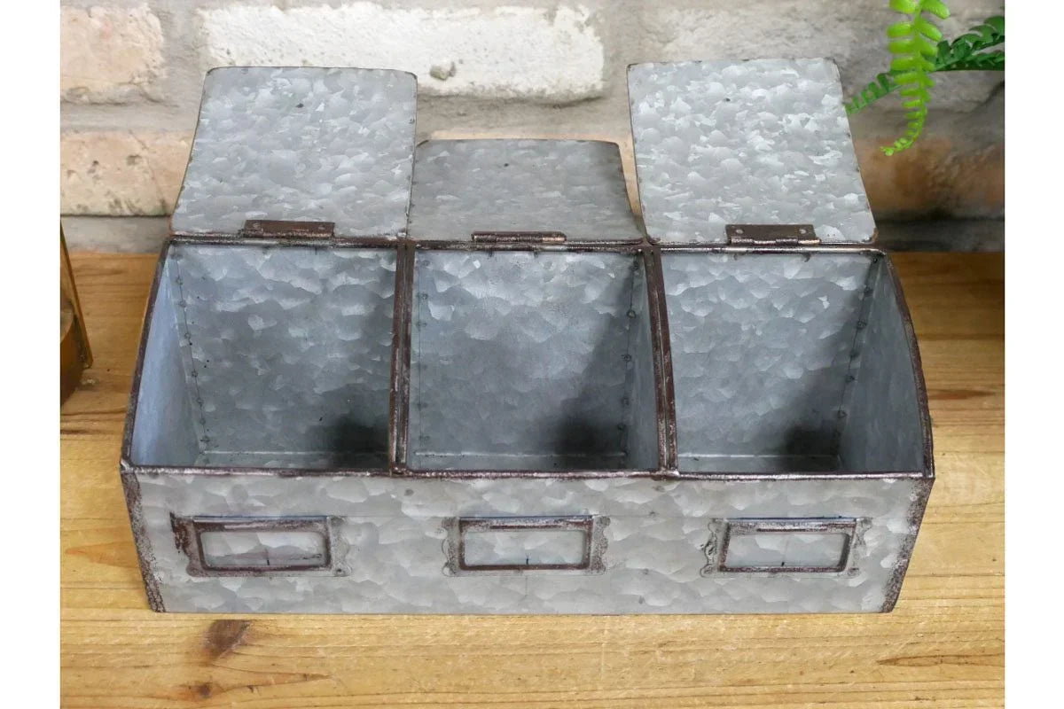Galvanized metal storage box with three compartments and hinged lids on wooden surface