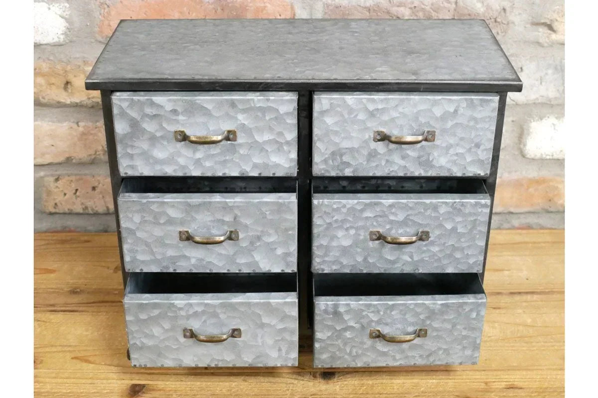 Galvanised metal drawer unit with six compartments and brass handles on wooden surface