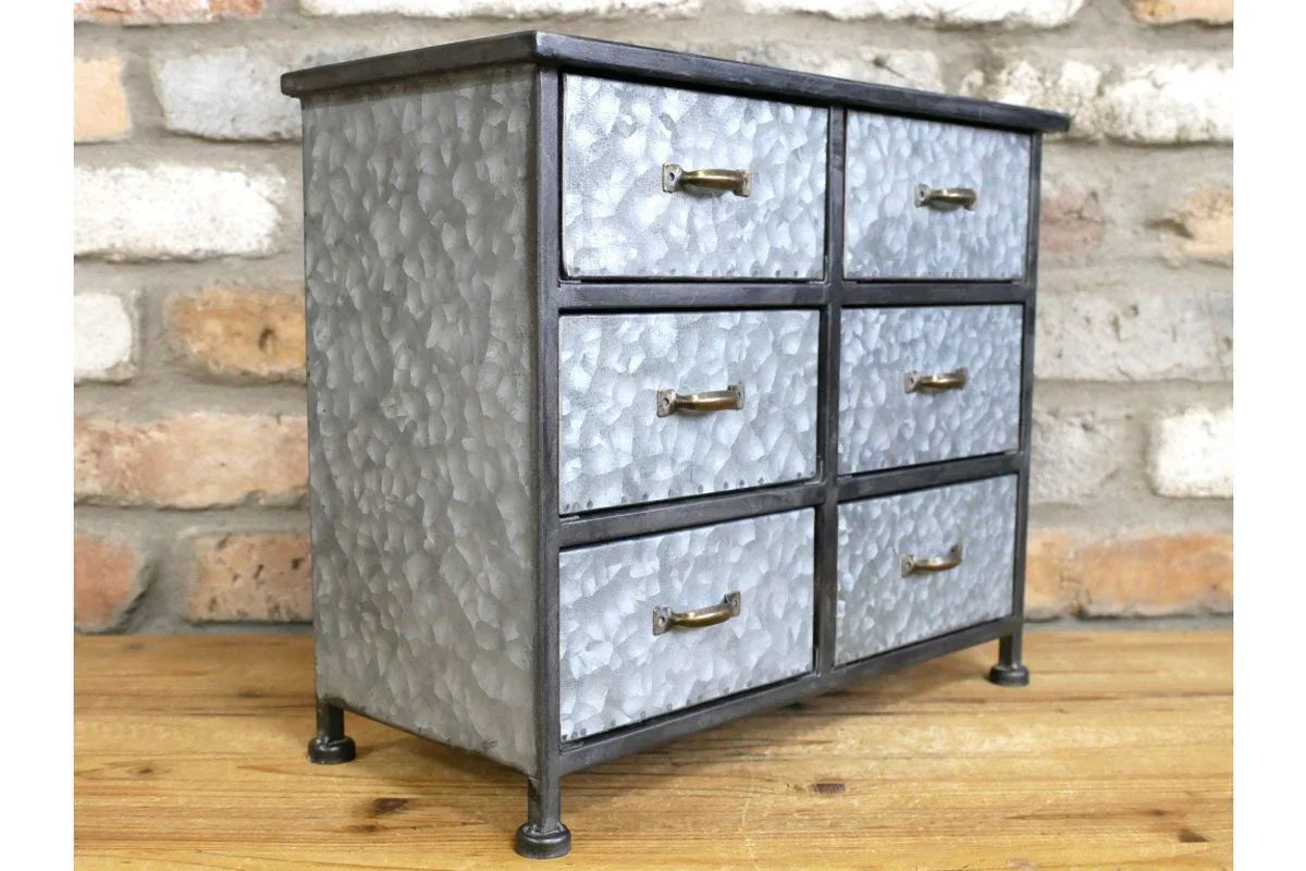 Industrial metal storage cabinet with six drawers and brass handles on wooden floor