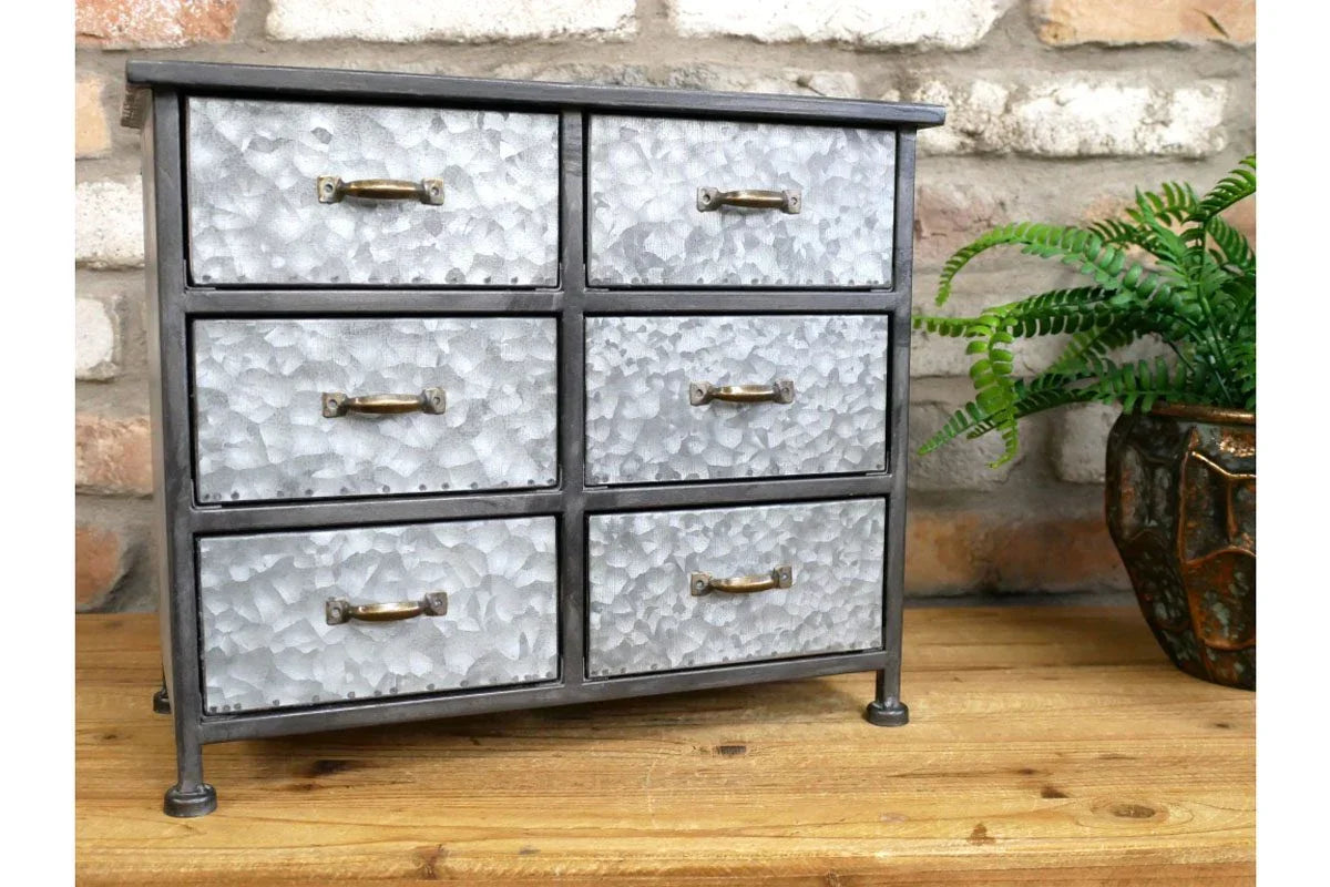 industrial metal storage chest with six textured drawers and brass handles on wooden surface