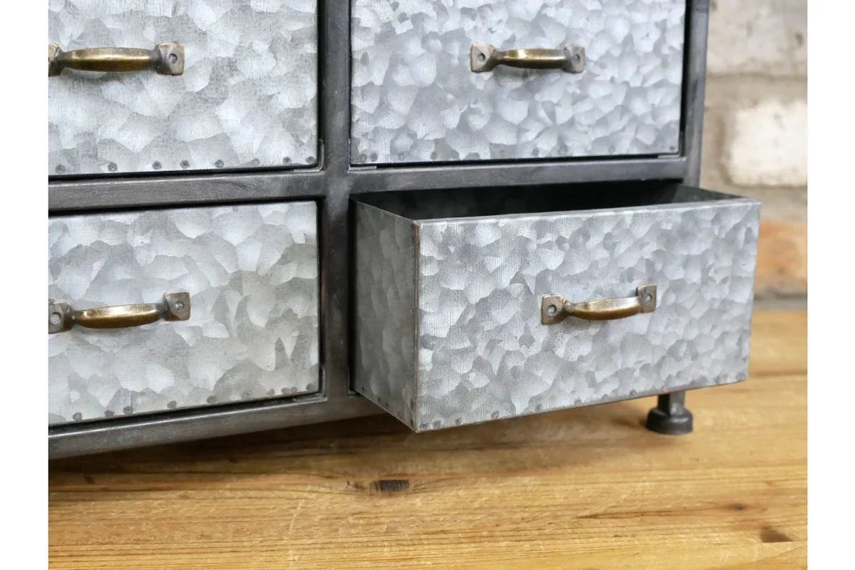 Industrial metal storage drawers with textured finish and brass handles on wooden surface