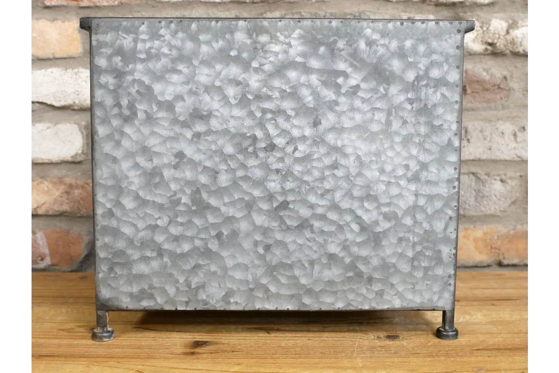 Galvanised metal storage box with textured finish and short legs on wooden floor