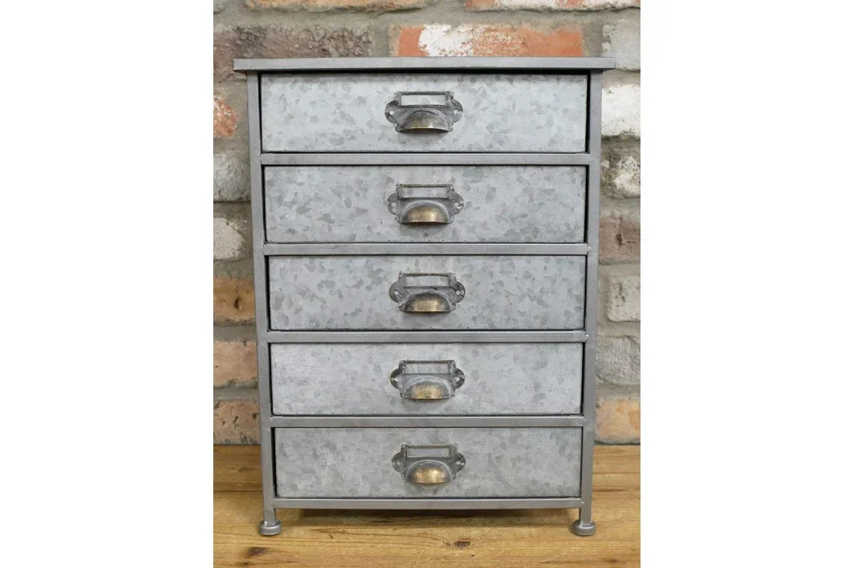 Industrial metal chest of drawers with five handles against exposed brick wall