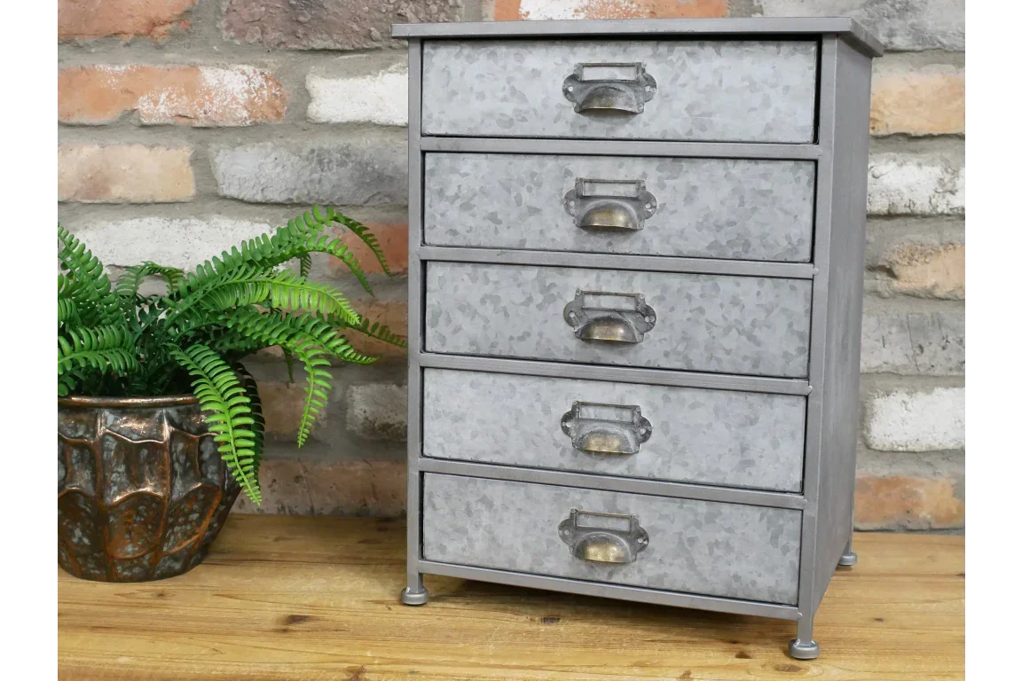 Galvanised metal chest of drawers with five drawers on wooden table, potted fern beside