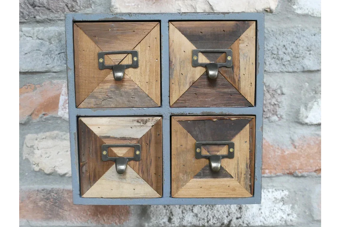 Rustic wooden storage cabinet with four small drawers and metal handles against brick wall