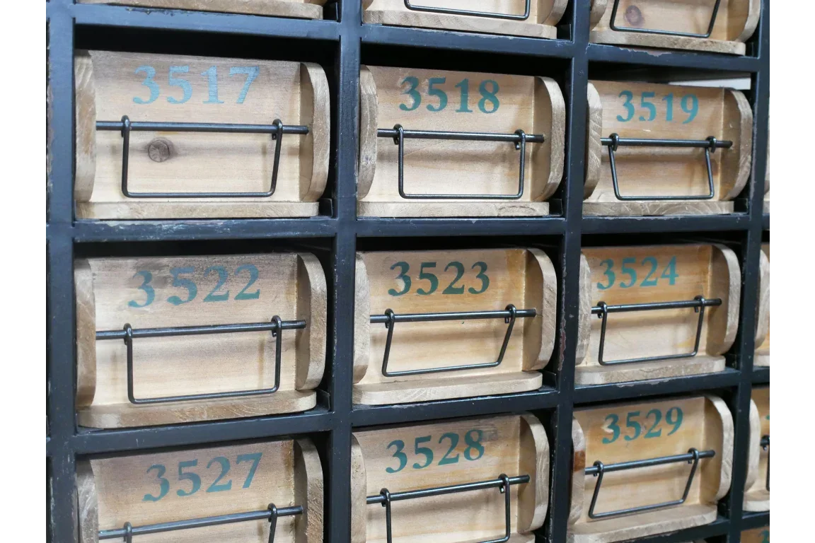 Wooden storage drawers with black metal handles and numbers in a black shelving unit
