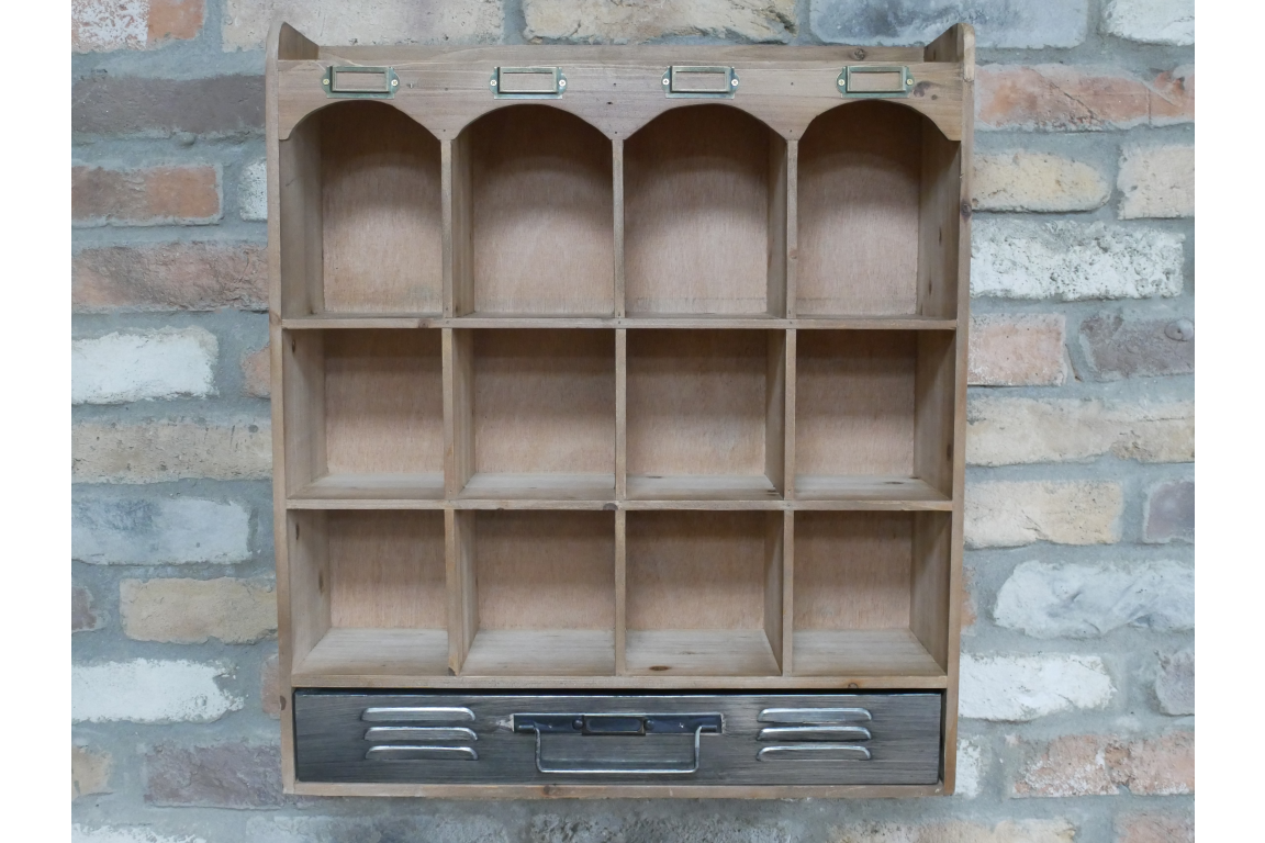 Wooden wall unit with twelve cubbyhole shelves, arched top compartments, black metal drawer front, mounted on brick wall.