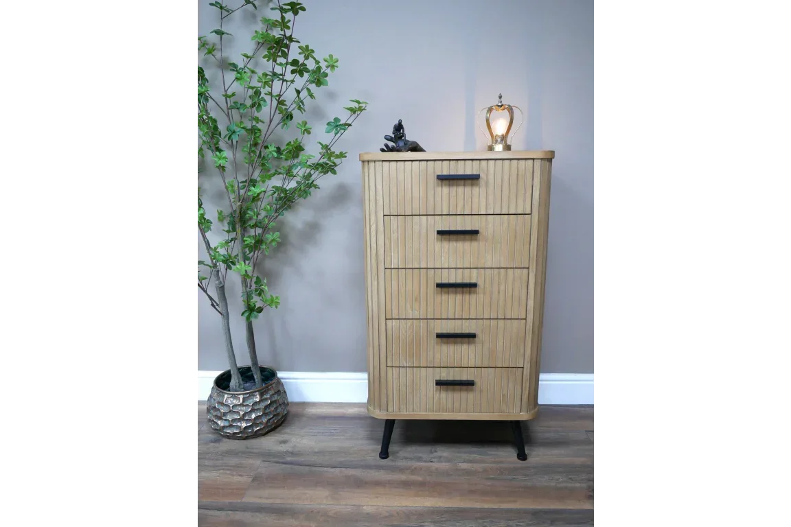 Tall wooden chest of drawers with black handles, modern design, beside indoor plant