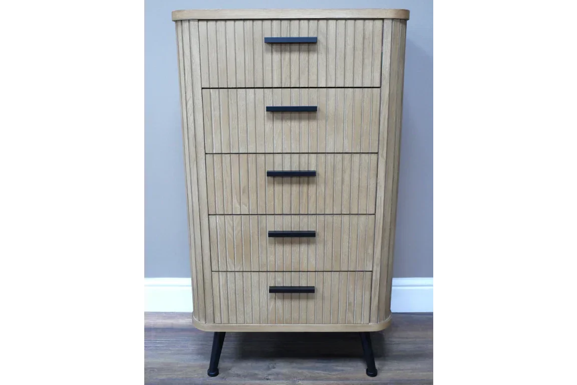 Tall wooden chest of drawers with vertical grooves and black metal handles on short legs