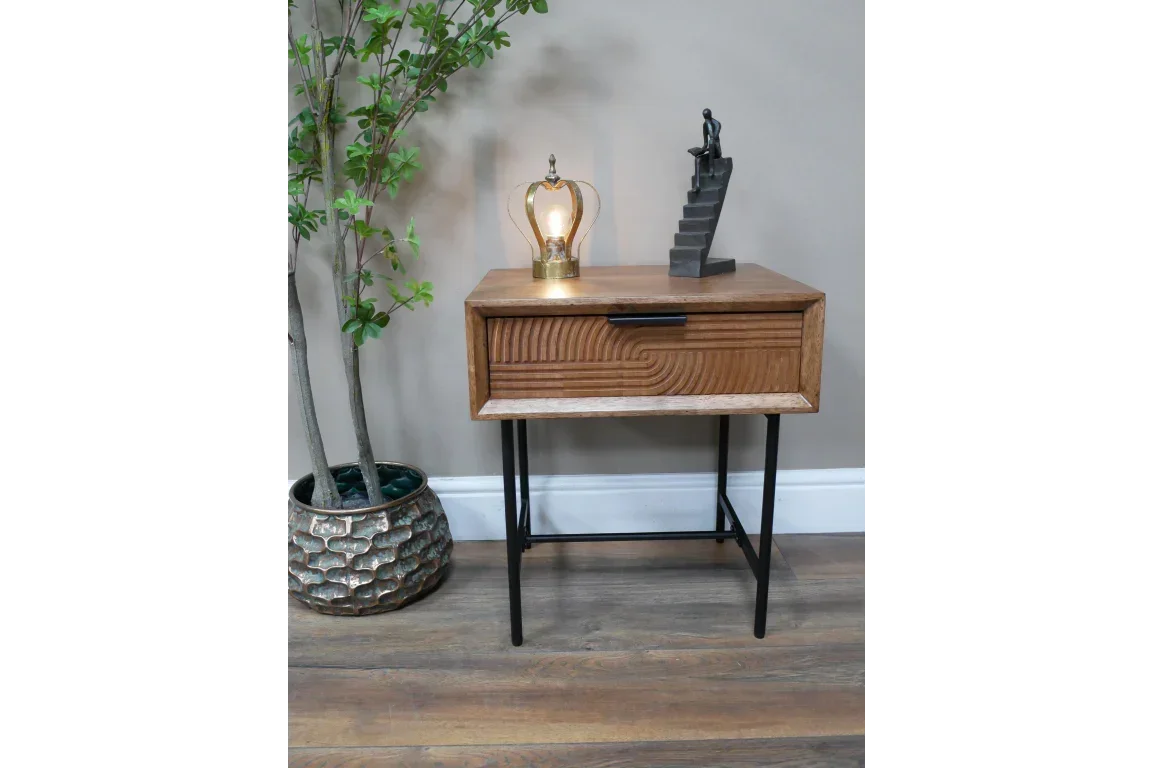 Wooden bedside table with black metal legs and single drawer, lamp and decor on top