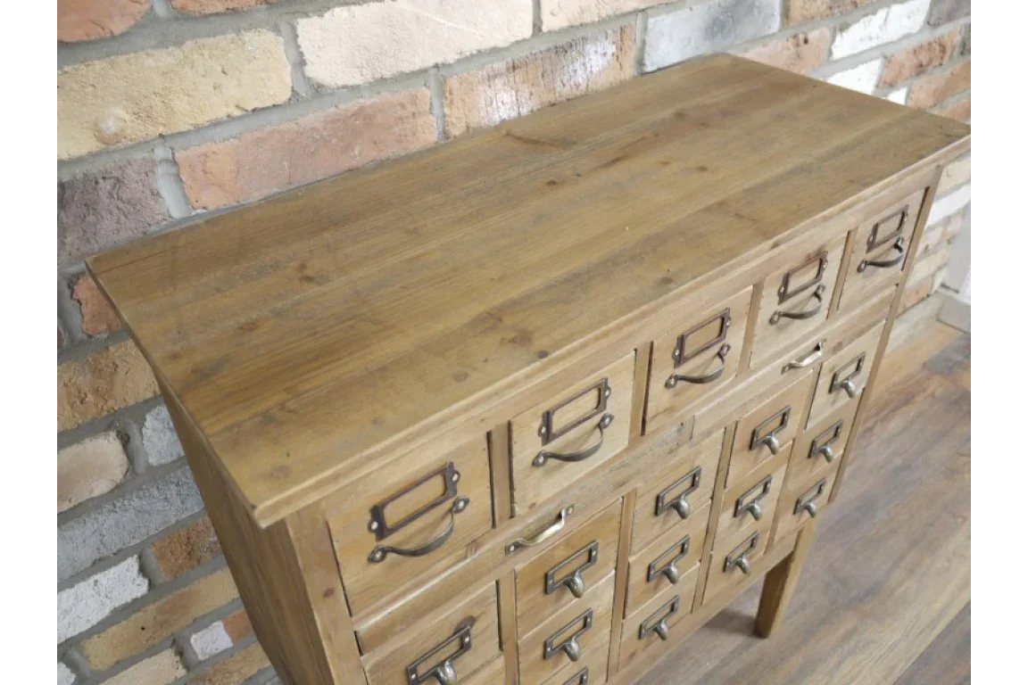 Rustic wooden chest of drawers with metal handles against a brick wall