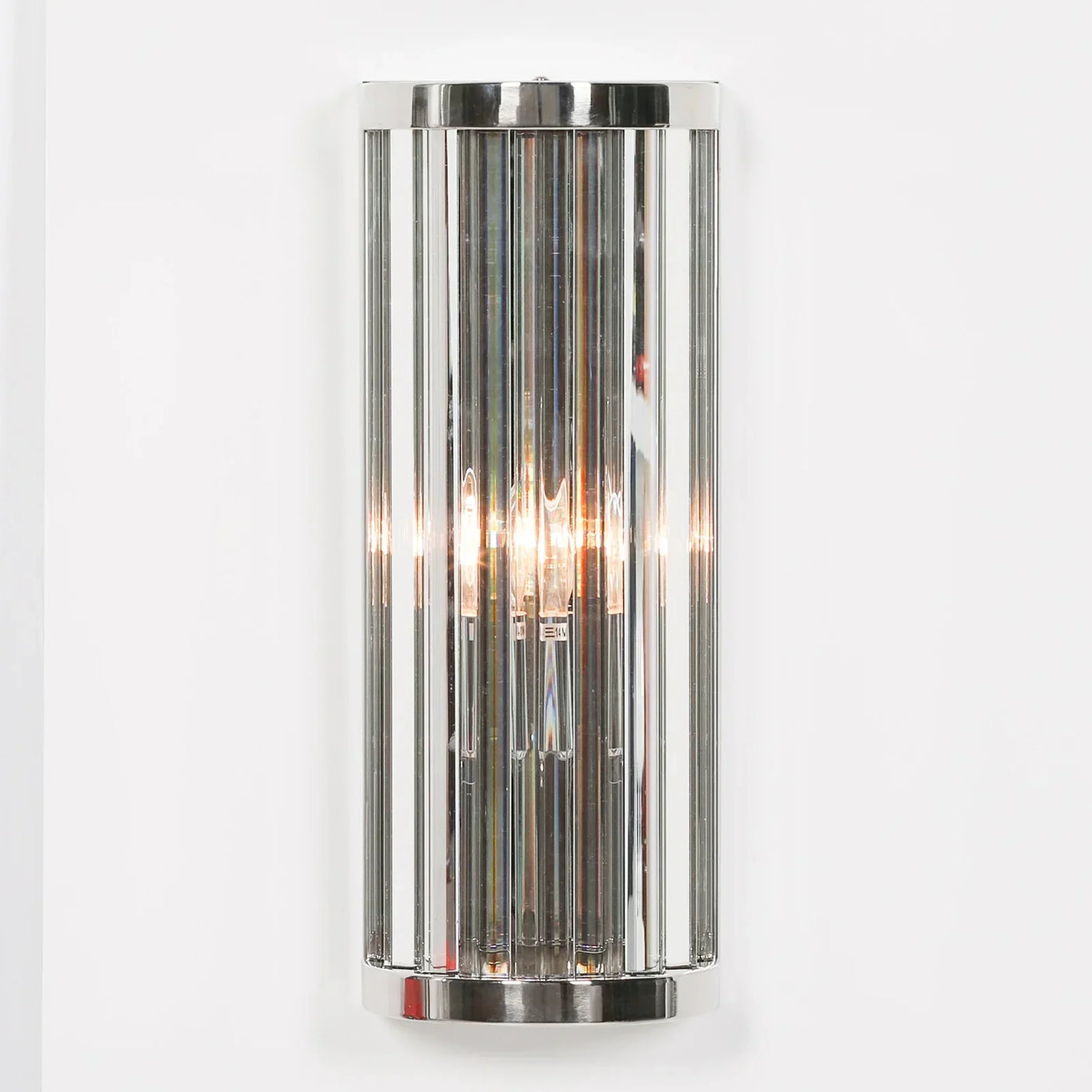 Chrome wall light with vertical glass panels mounted on white wall, modern lighting fixture