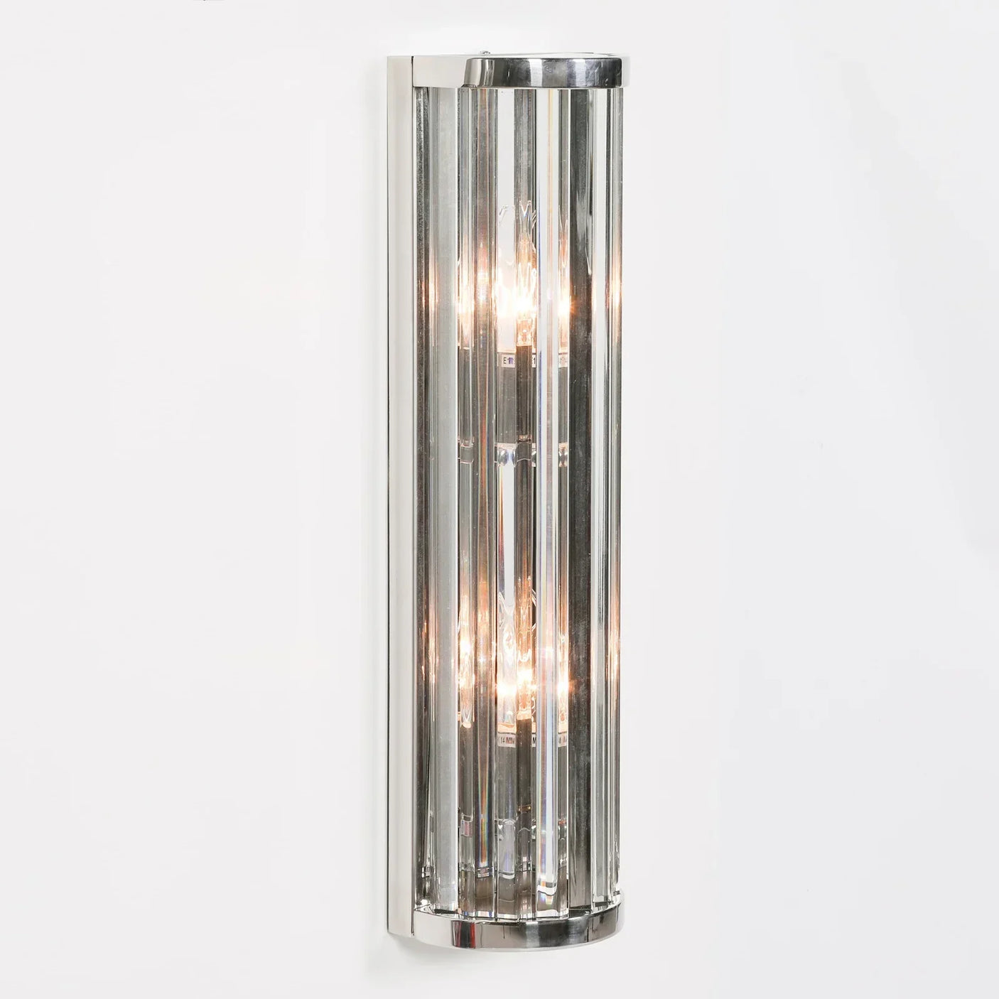 Modern chrome wall light with vertical glass rods mounted on white wall