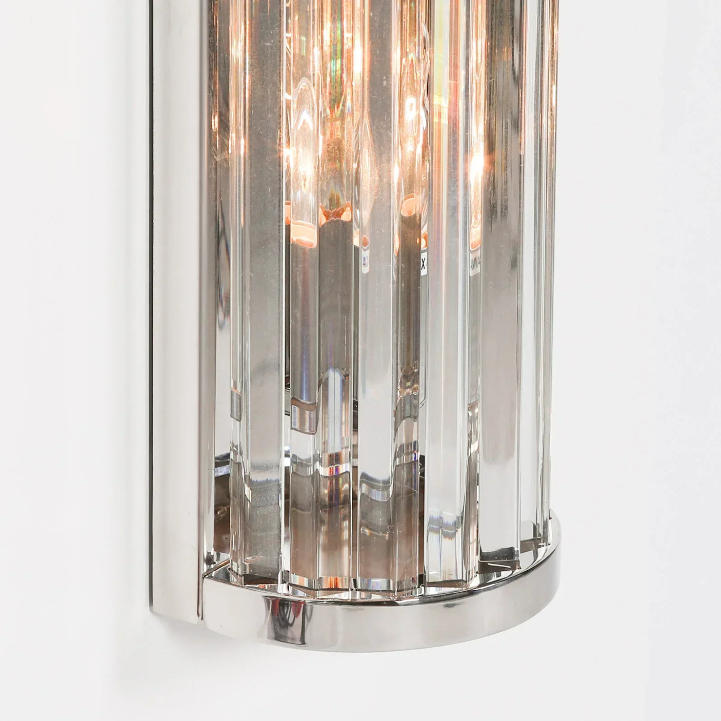 Chrome wall light with vertical glass panels and exposed bulbs on white background