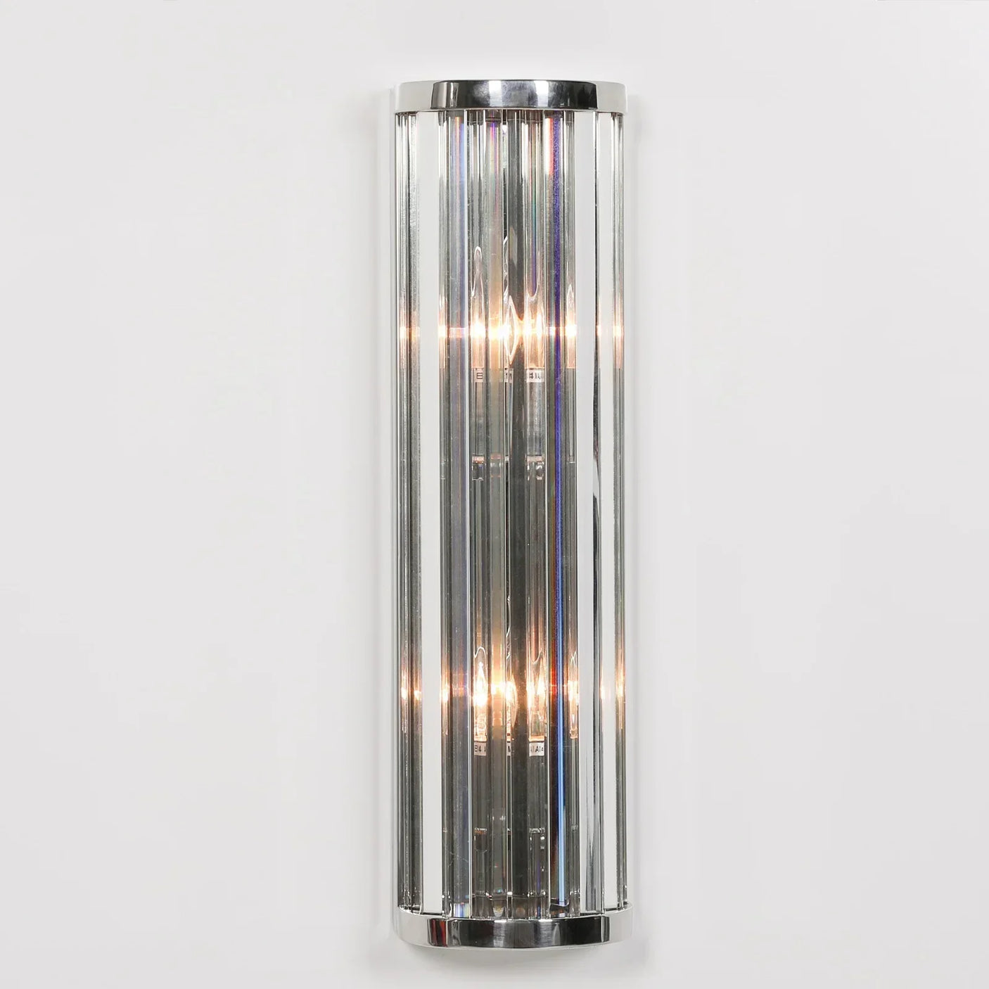 Chrome wall light with vertical glass rods and exposed bulbs against white wall
