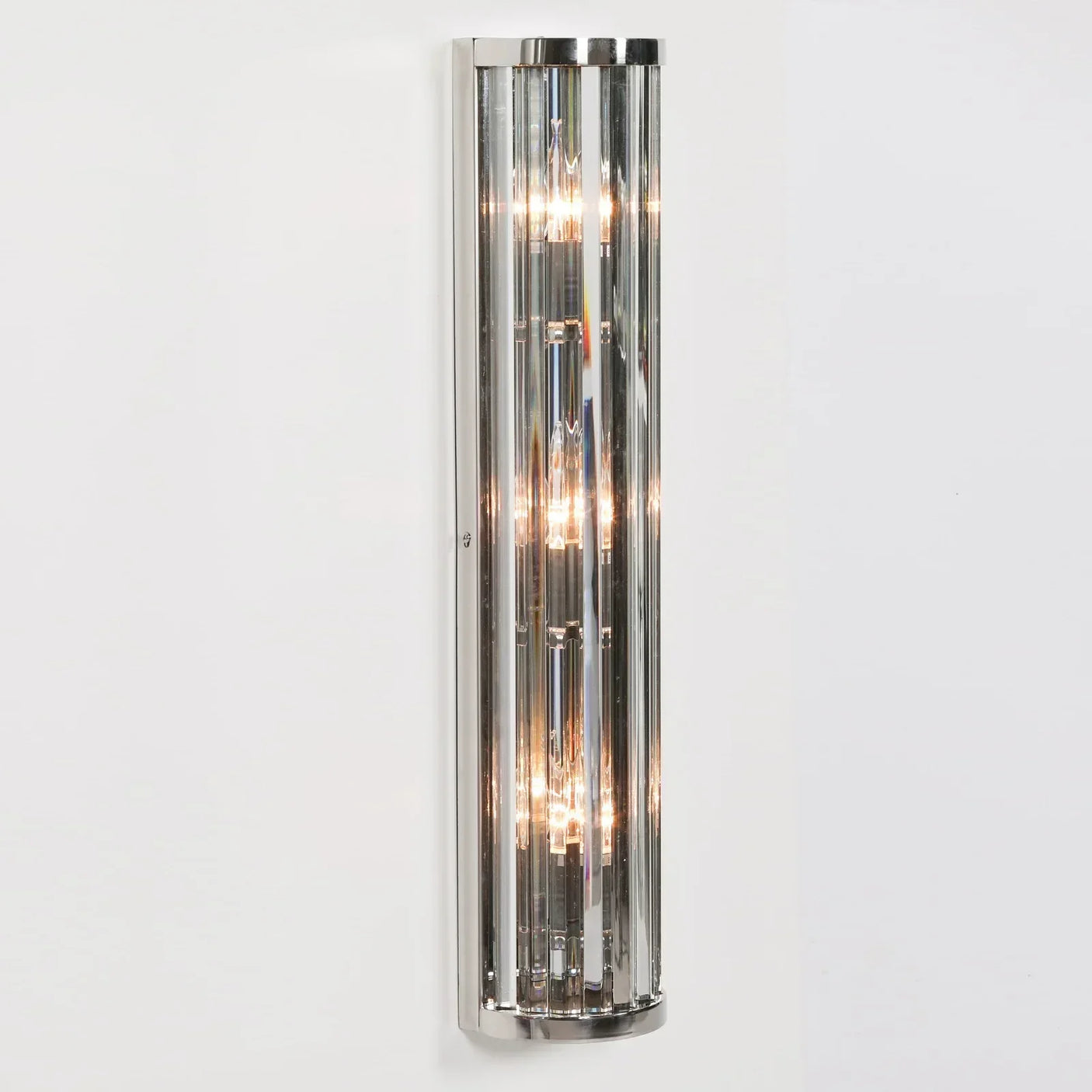 Modern wall light with chrome finish and vertical glass rods, mounted on a white wall