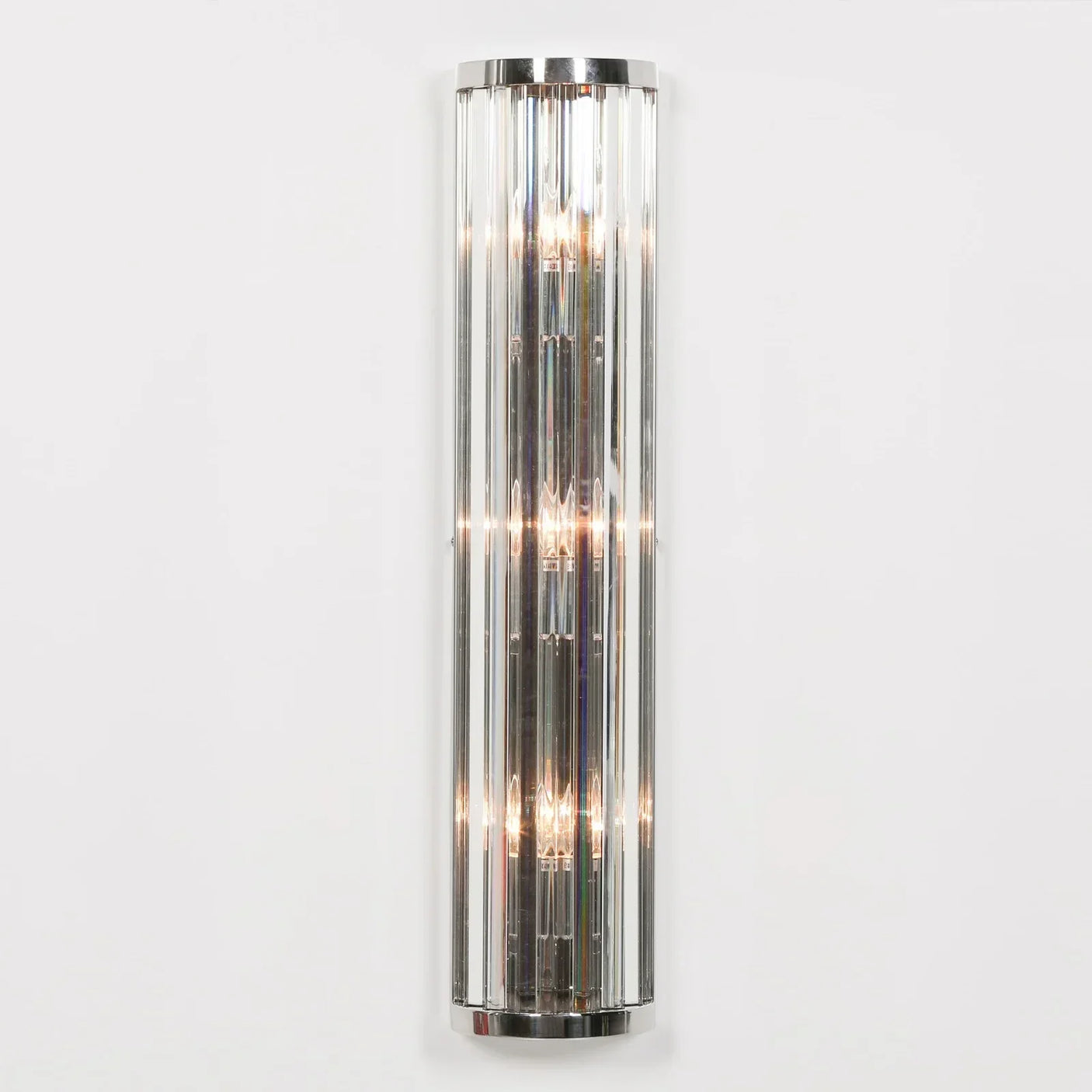 Chrome and glass wall light fixture with vertical crystal rods mounted on white wall