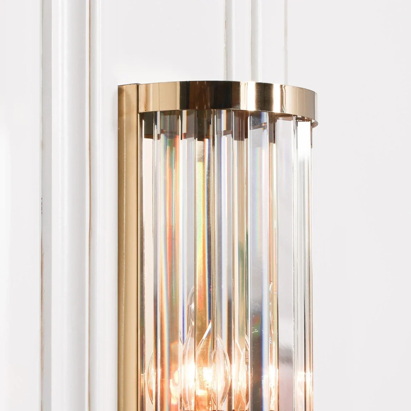 Glass and gold wall light with vertical prism detailing on white background
