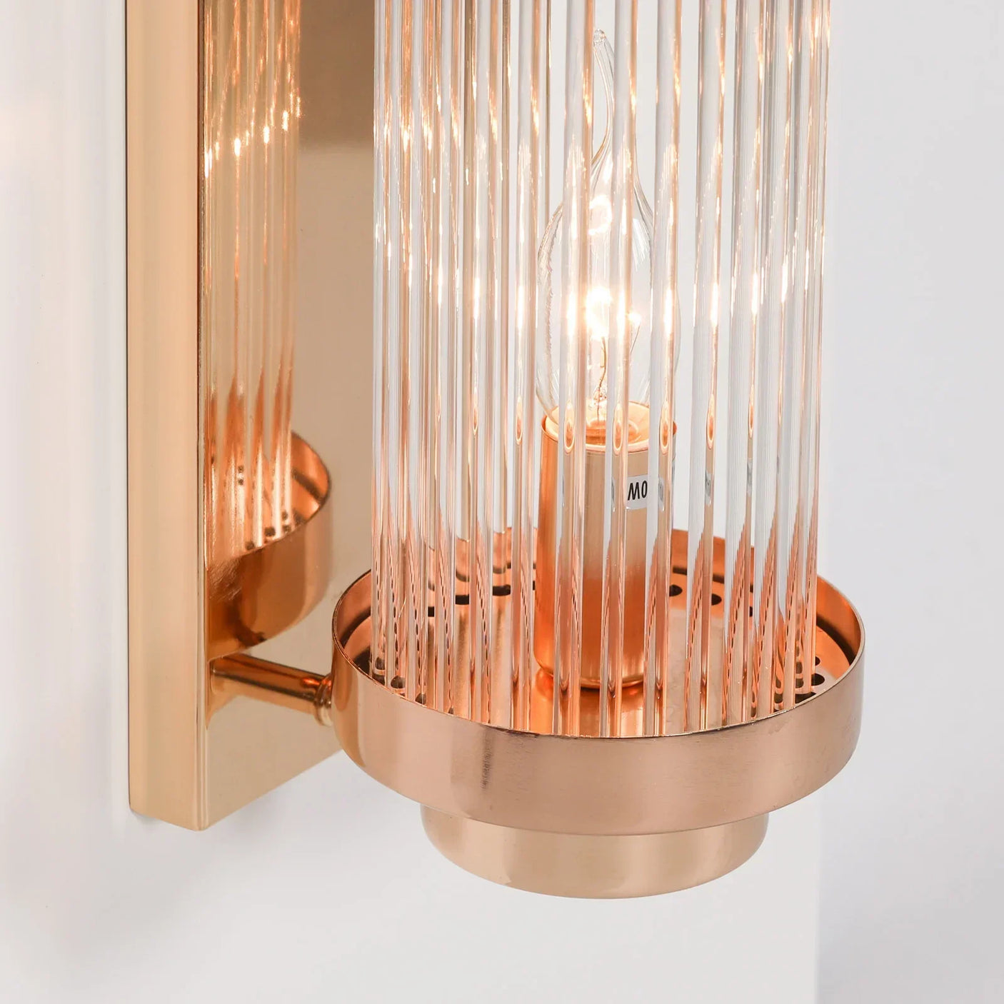 Glass and gold wall light with vertical ribbed shade and exposed candle-style bulb